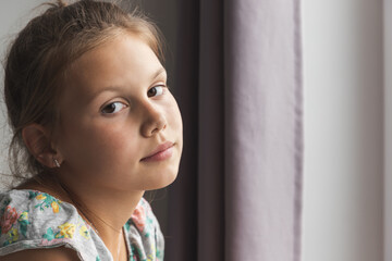 Close up portrait of little Caucasian girl sitting near the window