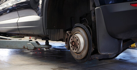 A modern car in a car service on a lift with a removed wheel. Brake check and repair. Selected...