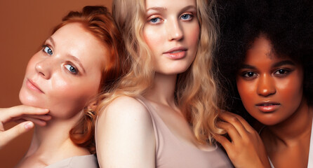 young pretty african and caucasian women posing cheerful together on brown background, lifestyle diverse nationality people concept