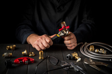Plumber connects the high pressure hose with a wrench to the water tap. Working environment in the workshop when connecting the boiler.