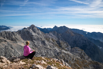 Naklejka na ściany i meble Female hiker sitting and relaxing on a mountain and enjoying beautiful view.