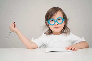 The doctor tells how to treat everyone. The child is playing doctor funny. A kid with glasses writes something on a piece of paper