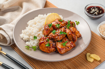 Teriyaki chicken with rice and fresh herbs in a beige plate. A traditional Japanese dish.