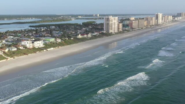 Aerial pan of Florida east coast barrier island beachfront community Wilbur By The Sea, showing beach, ocean surf, residential houses with sea walls, and the Atlantic Intracoastal Waterway.