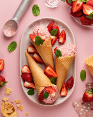 Delicious strawberry ice cream on pink plate and pink background with mint and silver ice cream spoon