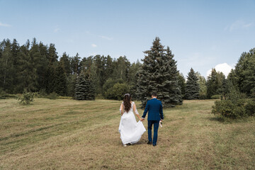 the groom and the bride go to the field, the newlyweds are walking in the woods
