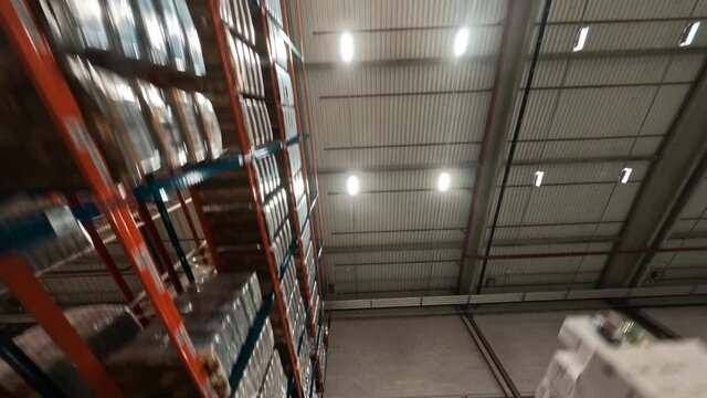 FPV drone view inside modern industrial retail delivery storage warehouse. Racks with cardboard boxes. Logistic center storehouse.