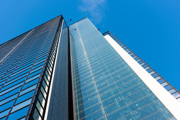 Obraz na płótnie Canvas Looking up tall glass and steel high-rise skyscraper.