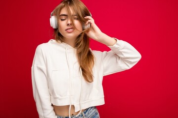 Photo of beautiful happy positive cool young blonde woman wearing white hoodie isolated over...