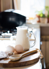 Fresh milk and eggs on wooden board in real home kitchen interior with natural light