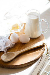 Fresh milk and eggs on wooden board in real home kitchen interior with natural light
