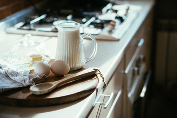 Obraz na płótnie Canvas Fresh milk and eggs on wooden board in real home kitchen interior with natural light