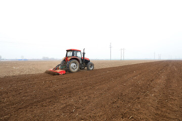 Obraz premium Farmers drive tractors to level up the land for planting corn on the farm.