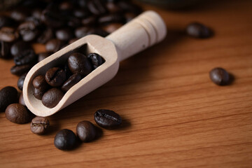 Fototapeta na wymiar fresh coffee beans in wooden spoon on wooden background