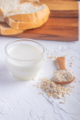oatmeal in wooden spoon and fresh milk on white background healthy food