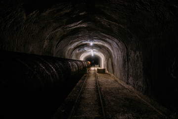 Fototapeta na wymiar Vaulted concrete underground tunnel of sewer, heating duct or water supply system
