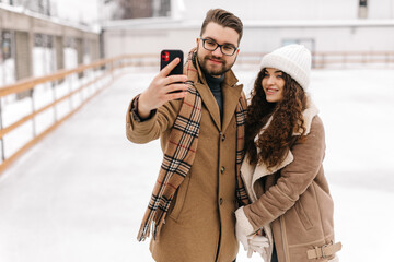 Happy couple taking a selfie in a figure skating field