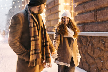Obraz na płótnie Canvas Lovely couple holding their hand in winter city at night