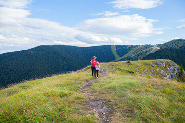 Fototapeta na wymiar Mother and daughter hiking on mountains at beautiful summer day.