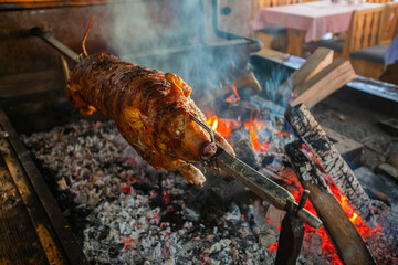 Delicious spit roasted suclinkg pig , grilled using hot charcoal. Fire place in the restaurant. - obrazy, fototapety, plakaty