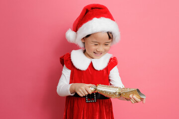 young girl playing Christmas cracker against pink background