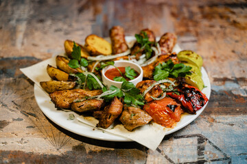 plate with Caucasian shish kebab, baked potatoes and vegetables on the grill close-up
