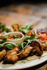 plate with Caucasian shish kebab, baked potatoes and vegetables on the grill close-up, free space for text

