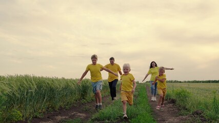 Happy family, children, sons, mom dad run, play, rejoice, enjoy nature in summer. Family teamwork. Family team, running together in field, happily waving their hands. Group of people of different ages