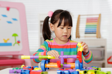 young girl playing water pipe construsction toy at home