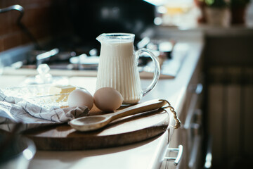 Fresh milk and eggs on wooden board in real home kitchen interior with natural light