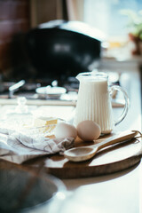 Fresh milk and eggs on wooden board in real home kitchen interior with natural light