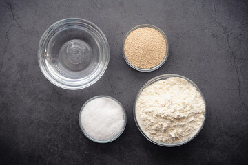 Overhead View of Ingredients for French Bread Baguette: Flour, yeast, sugar, and salt in a dark background