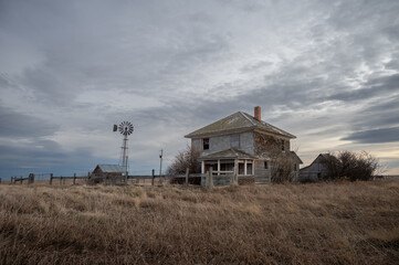 Obraz na płótnie Canvas Abandoned farmhouse in rural alberta Canada with cloudy skies