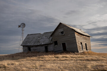 Fototapeta na wymiar Abandoned farmhouse in rural alberta Canada with cloudy skies