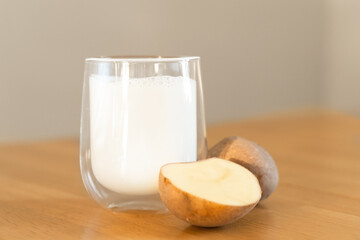 Potato milk photo on wooden background. Glass of alternative milk. Plant based vegetarian beverage. Lactose free drink