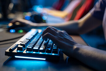 Man holding hands at computer keyboard while playing at online game during the streaming