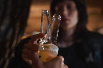 Man and woman clinking with bottles with beer while spending their date at evening street