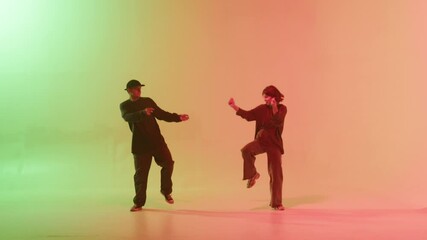 Professional choreographers dancing hip hop on color changing neon background. Man and woman dancers showing movements, pair dance, duet. Modern dance school for teenagers. - Powered by Adobe