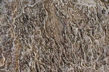 Rough stone surface with hint of warm yellow color. Abstract background for design.