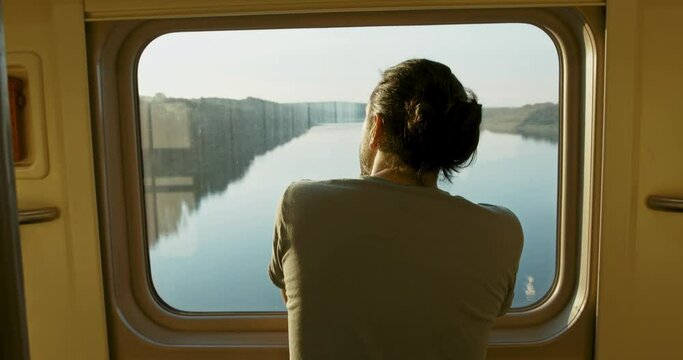 Young attractive tourist, looker out of the window of a moving train at sunset
