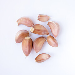 Close-up of a group of garlic cloves on a white background, top view.