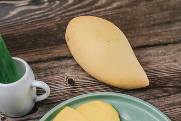 Delicious mango sticky rice serve with coconut milk on wooden table. Popular traditional dessert of Thailand.