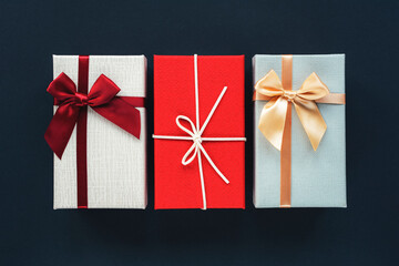 Three gift boxes on black background. Christmas concept. Top view, flat lay, copy space