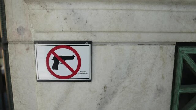 This panning video shows a no fire arms sign outside of a building.