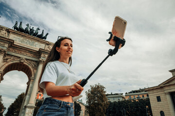 Travel influencers Milan island. Paint building house in Europe Milano. Photographer blogger girl with smartphone in Piazza del Duomo, Cathedral Square. Traveling and freelancing, modern lifestyle.