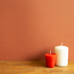 Red and white candles on wooden table. red brown background. copy space