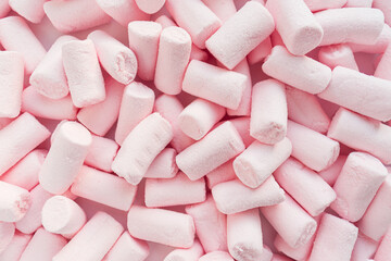 Lots of pink marshmallows are scattered over the surface. Close up. Selective focus.