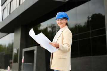 Female industrial engineer in hardhat with house plan outdoors
