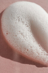 Texture of white foam on a pink background.