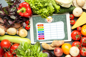 Tablet computer with meal plan and healthy products on grey background